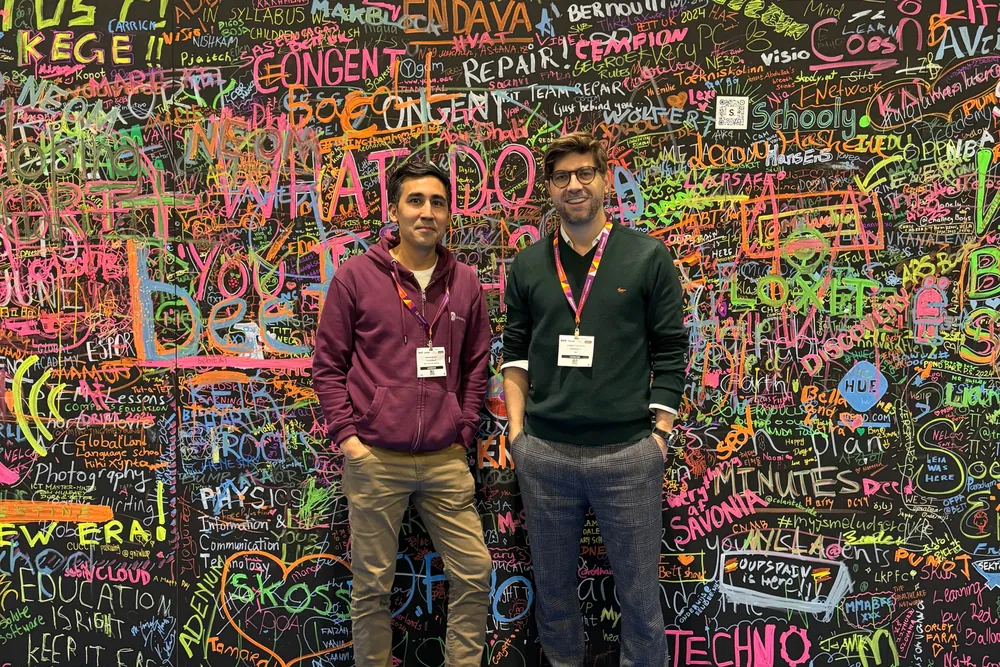 Two of the team in front of a graffiti wall at the Bett show