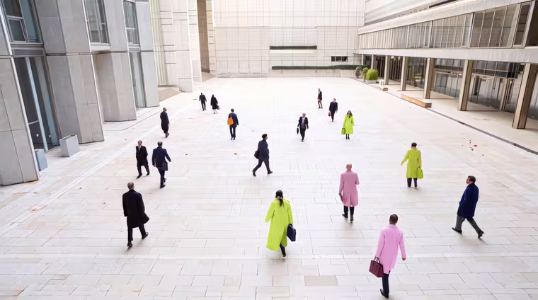 Executives crossing the plaza of a business district, seen from above.