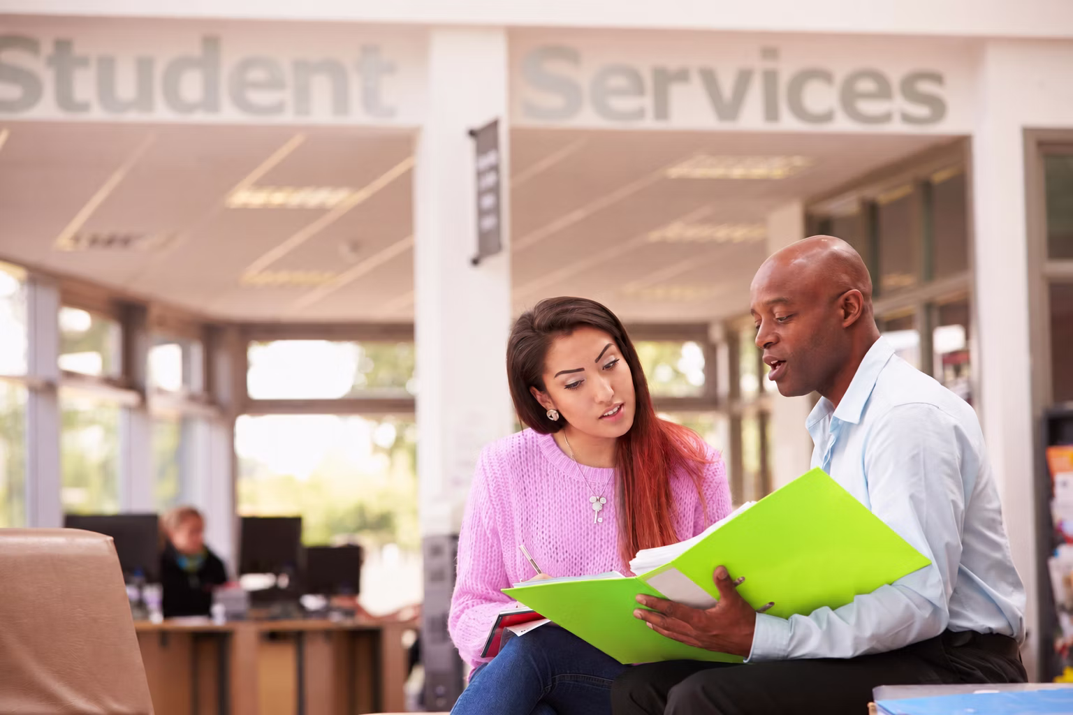 An adviser and a student talking in a student services area.