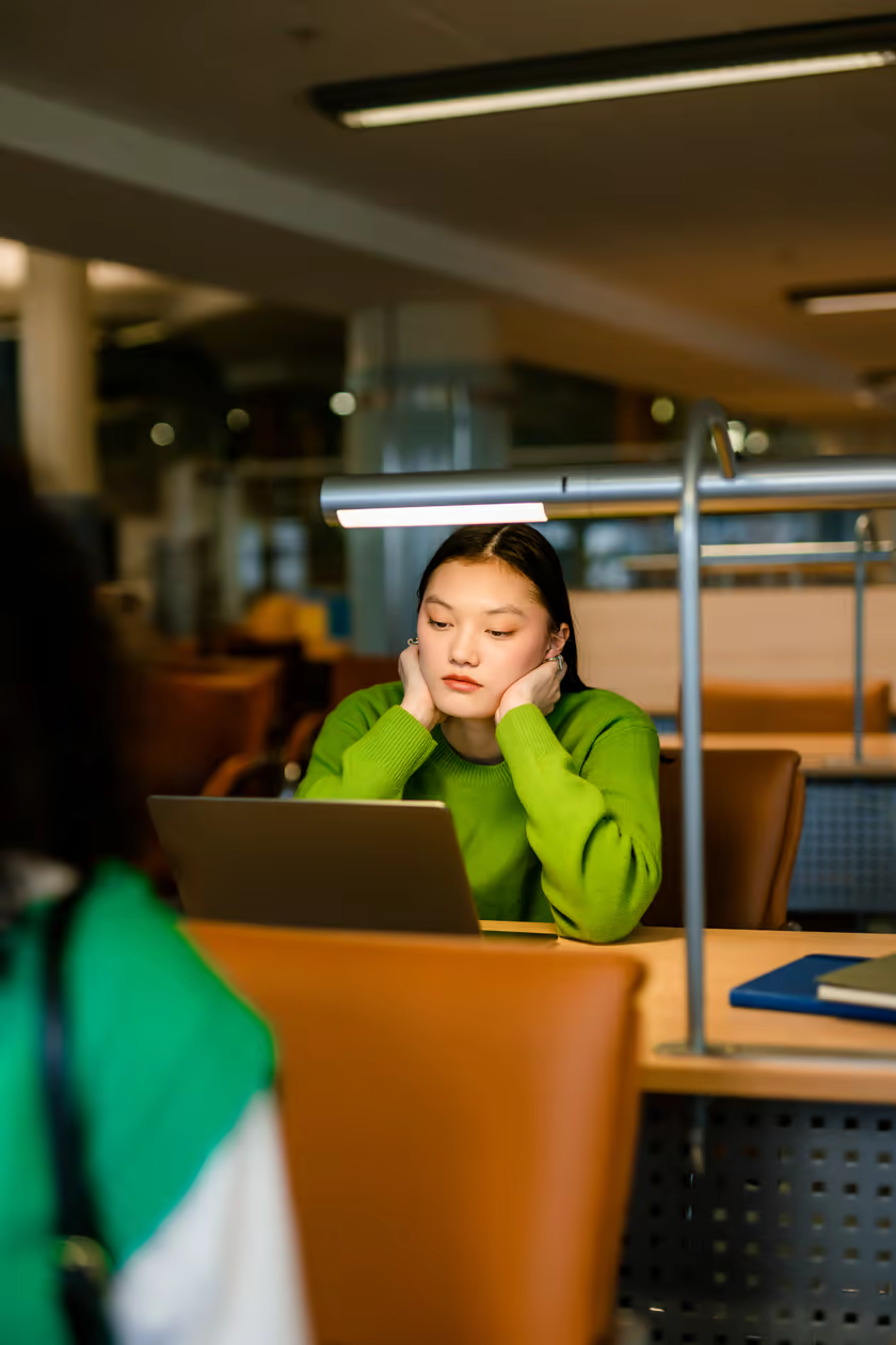 A student working at a laptop in a university library.