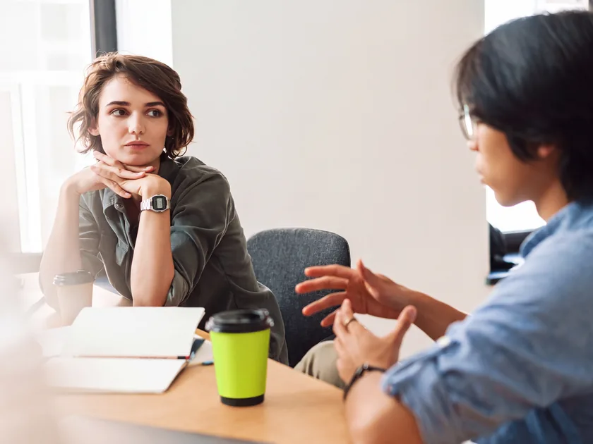 A career adviser talking a student through her results, a lime coffee cup on the table.