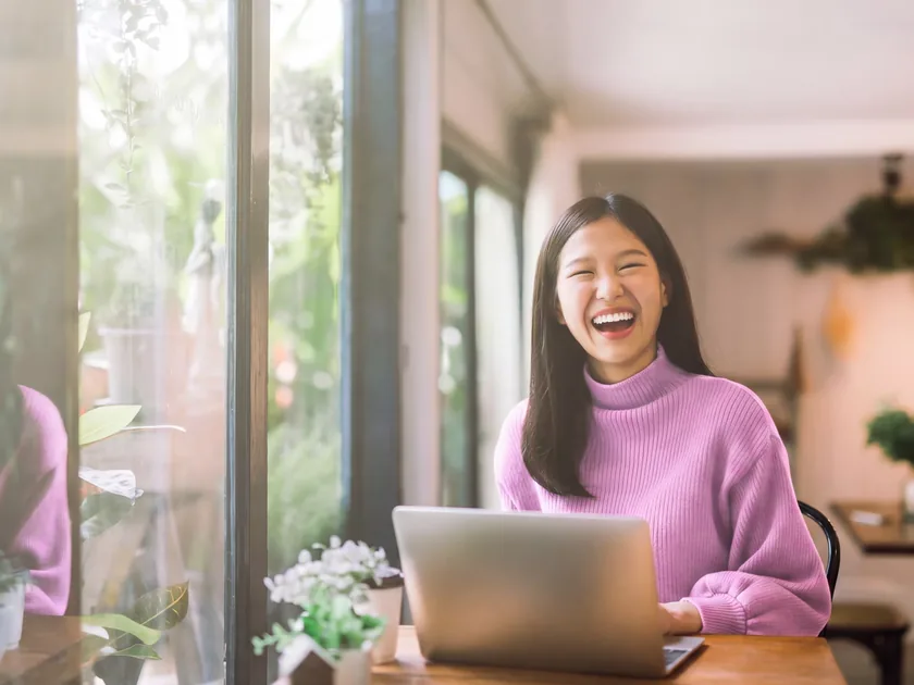 A student laughing at her laptop, between classes.