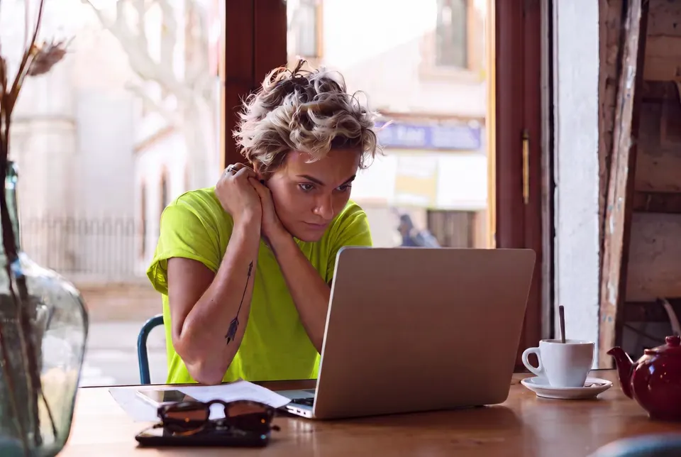 A student working at a laptop in a café, writing up a piece of evidence.