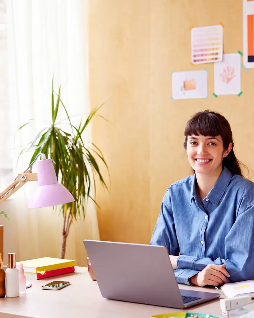 A student at a home desk with a laptop and a wall of notes.