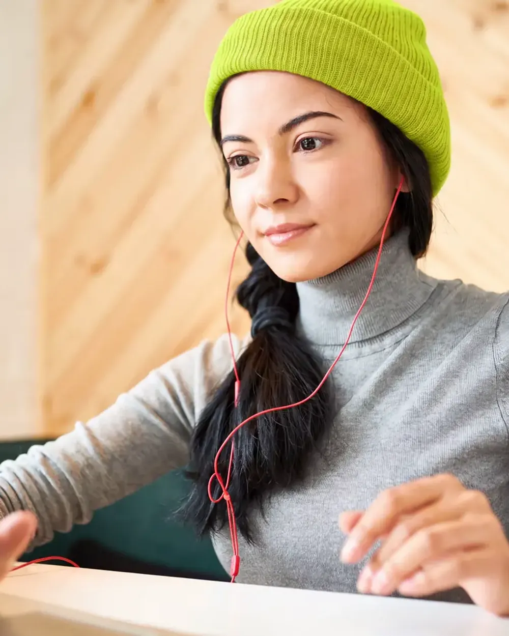 A student in a lime beanie, pausing to think between notes.